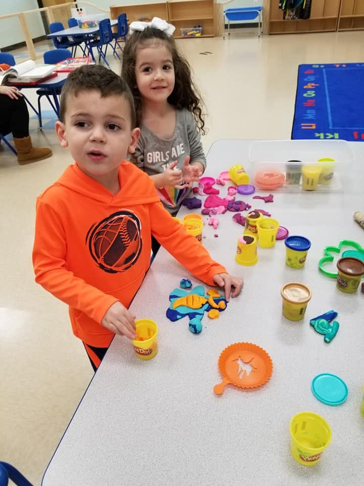 Two children playing with modeling clay at a table