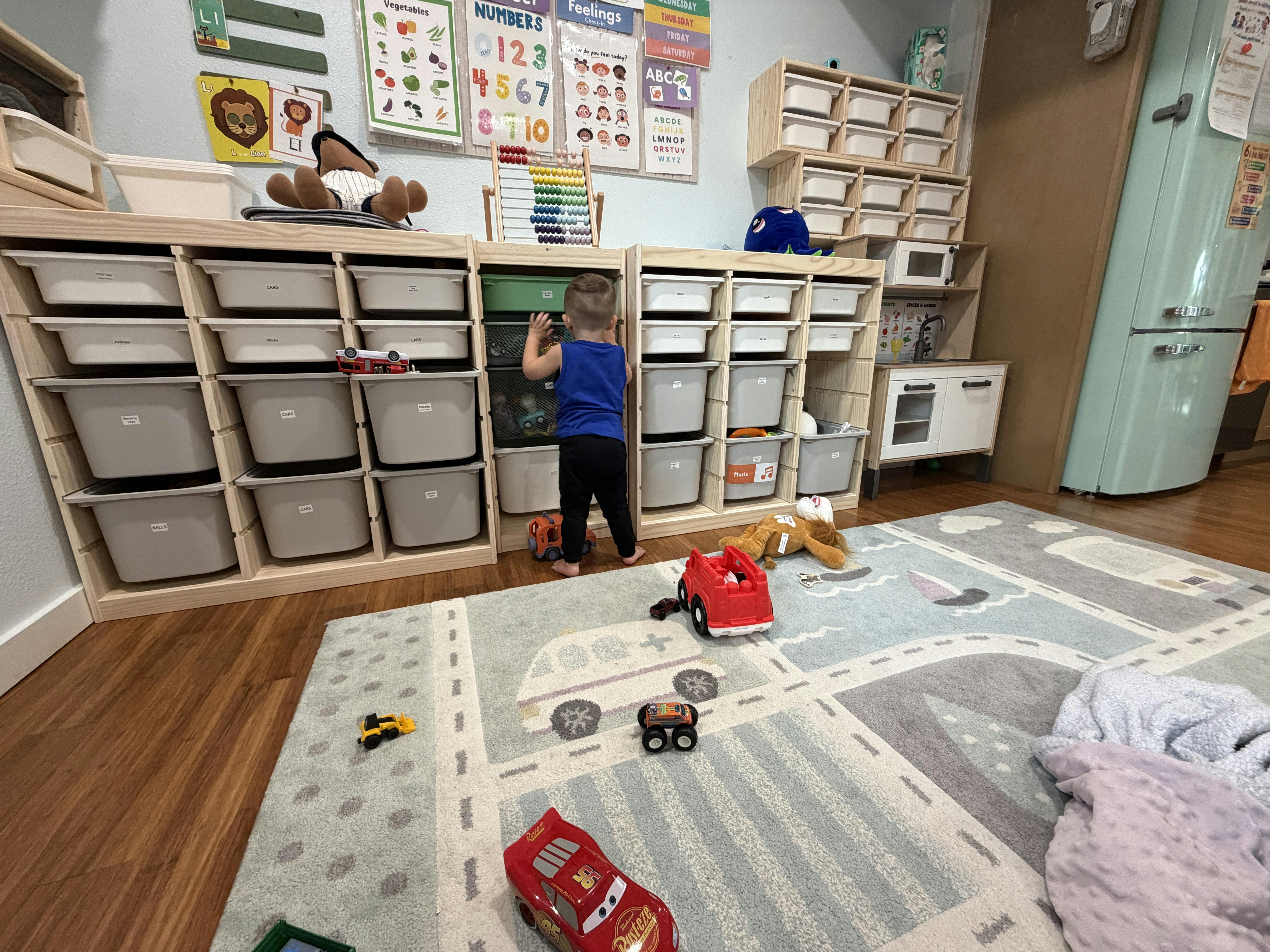 Child reaching into a toy storage bin in a playroom