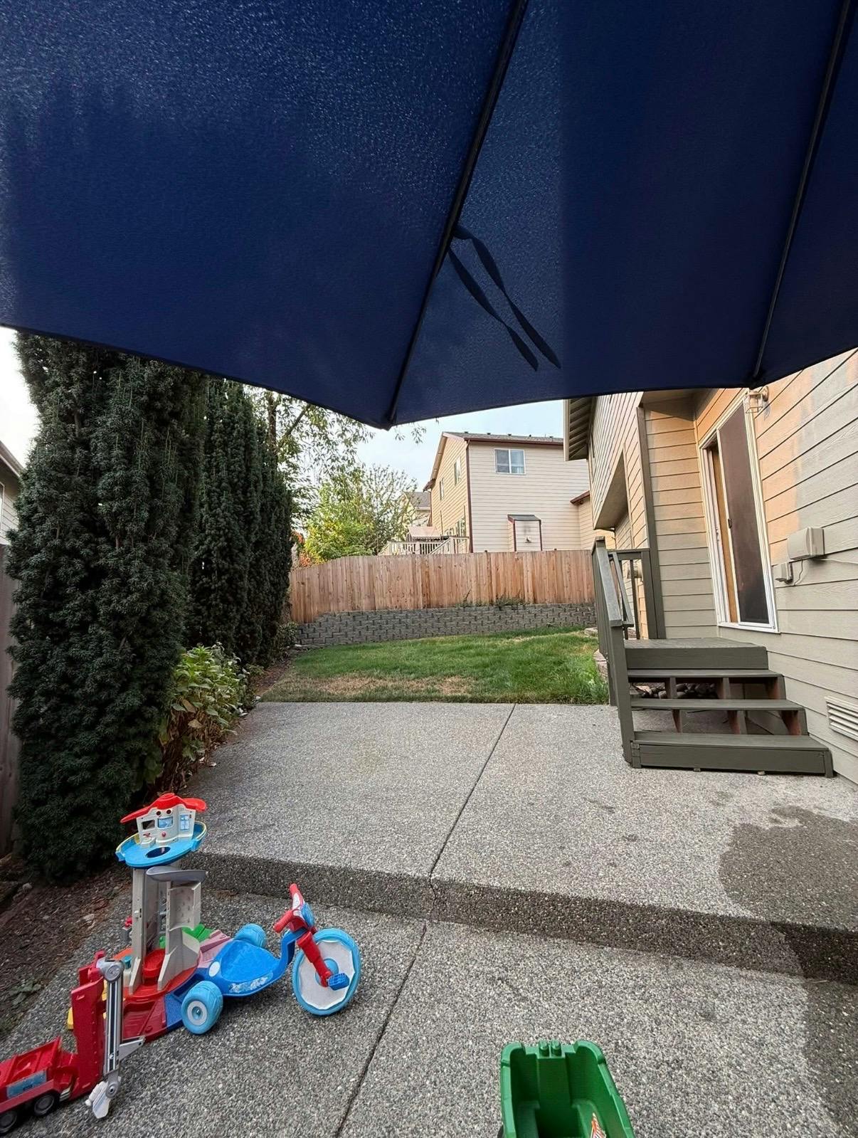 Backyard patio with children's toys and stairs leading to a house