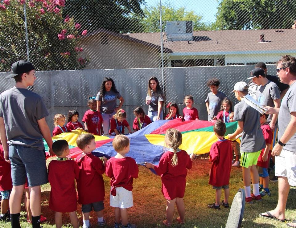 Adults and children playing with a colorful parachute outdoors