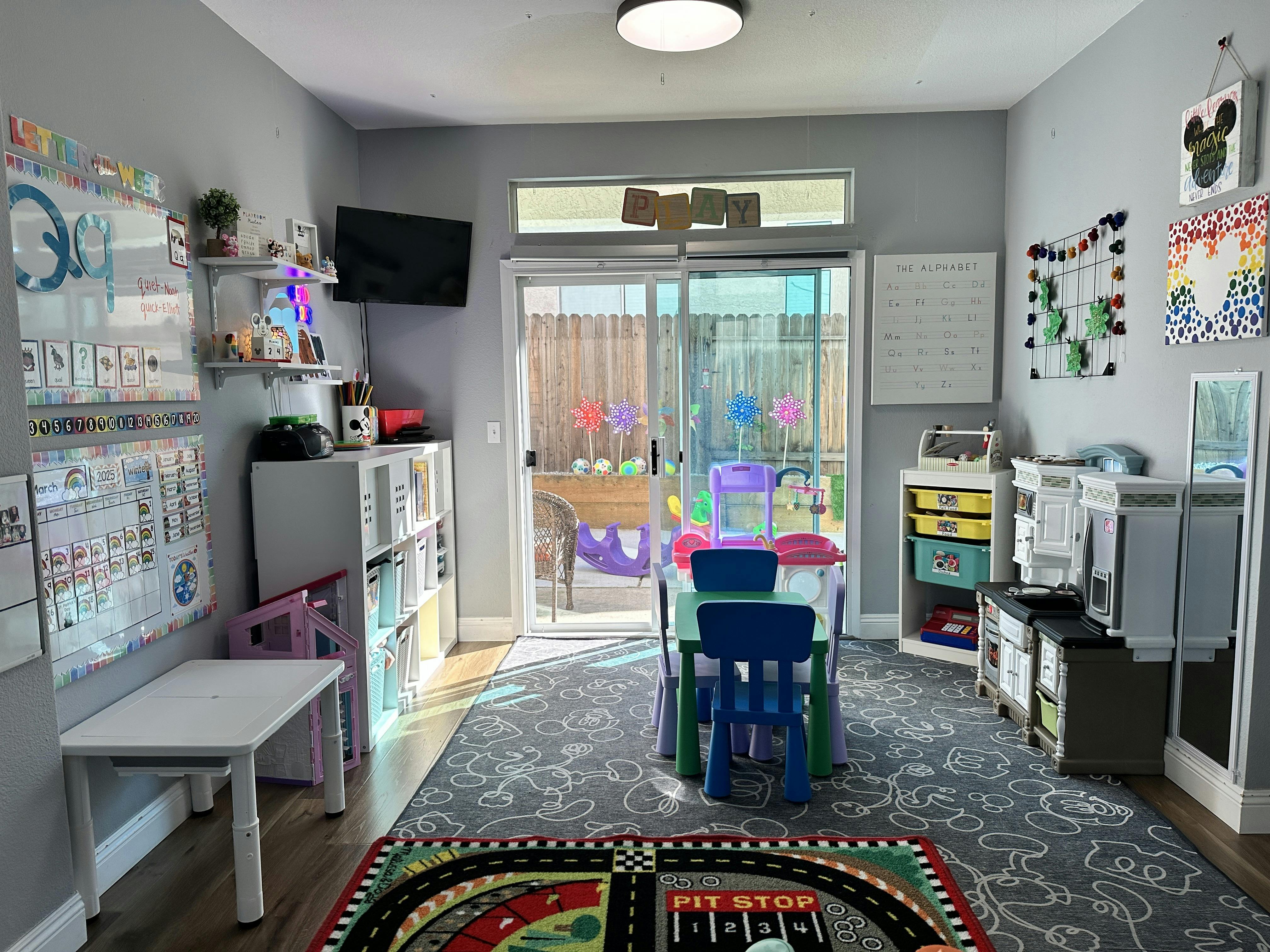 Playroom with small table and chairs, shelves, and sliding glass door to yard