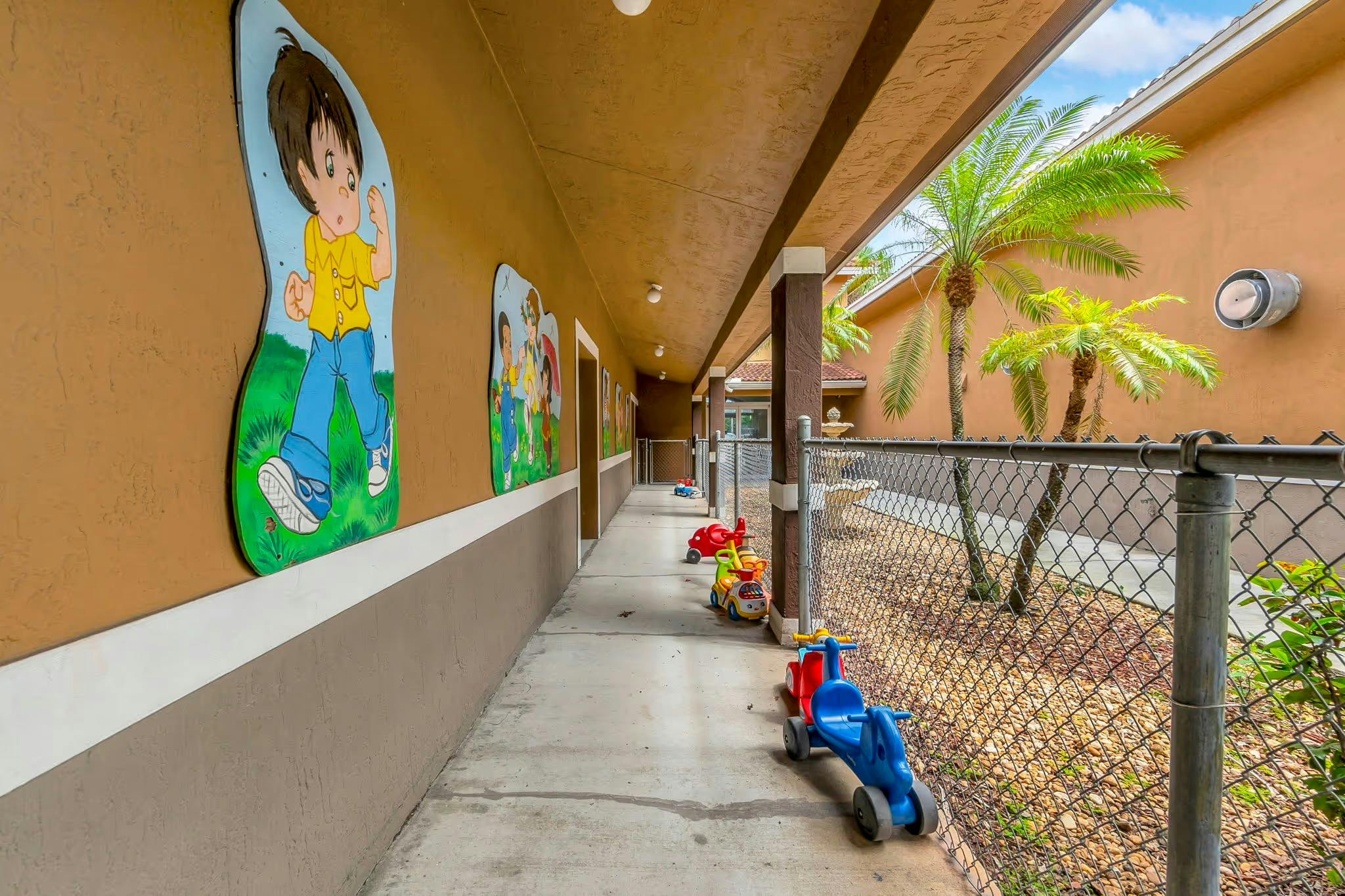 Outdoor walkway with cartoon cutouts on the wall and small ride-on toys