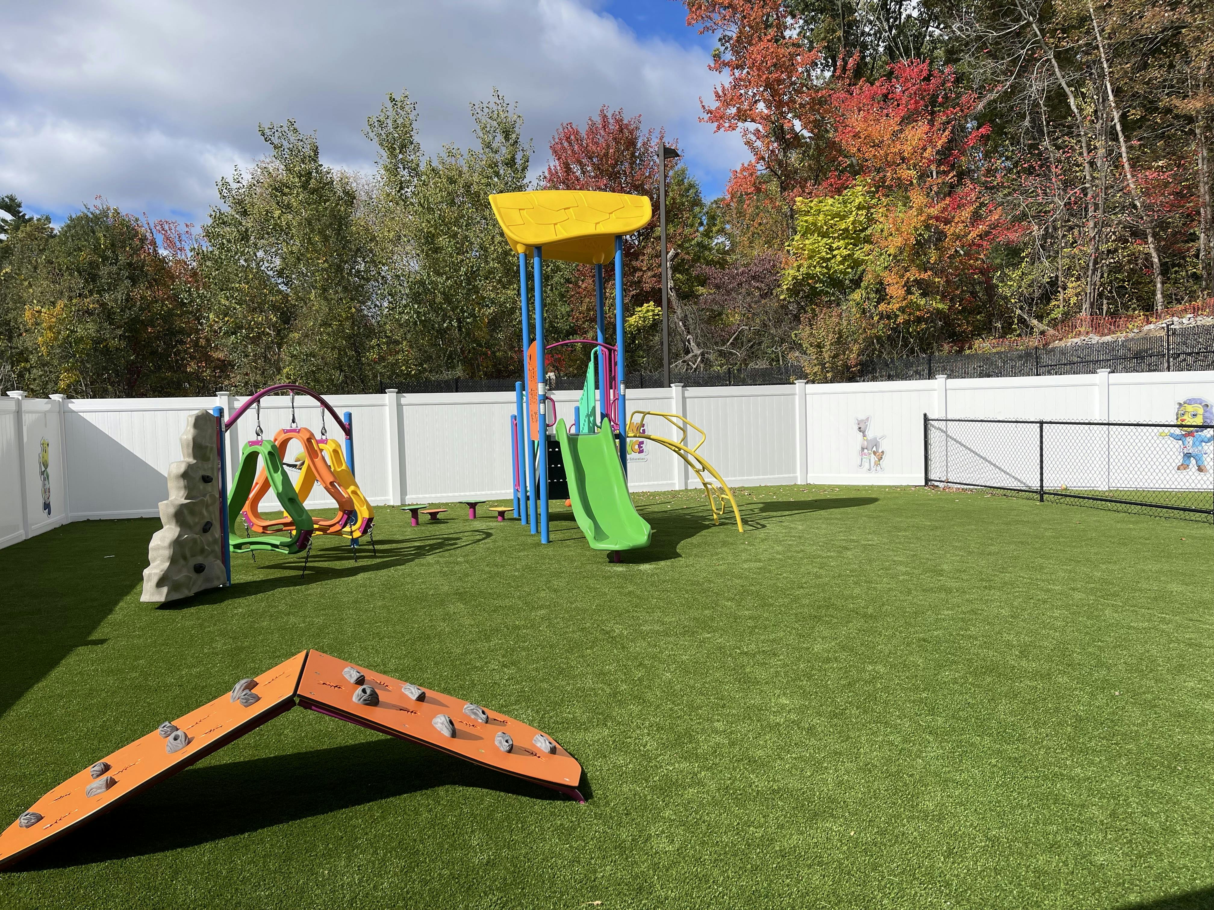 Outdoor playground with slides, climbing structures, and artificial turf