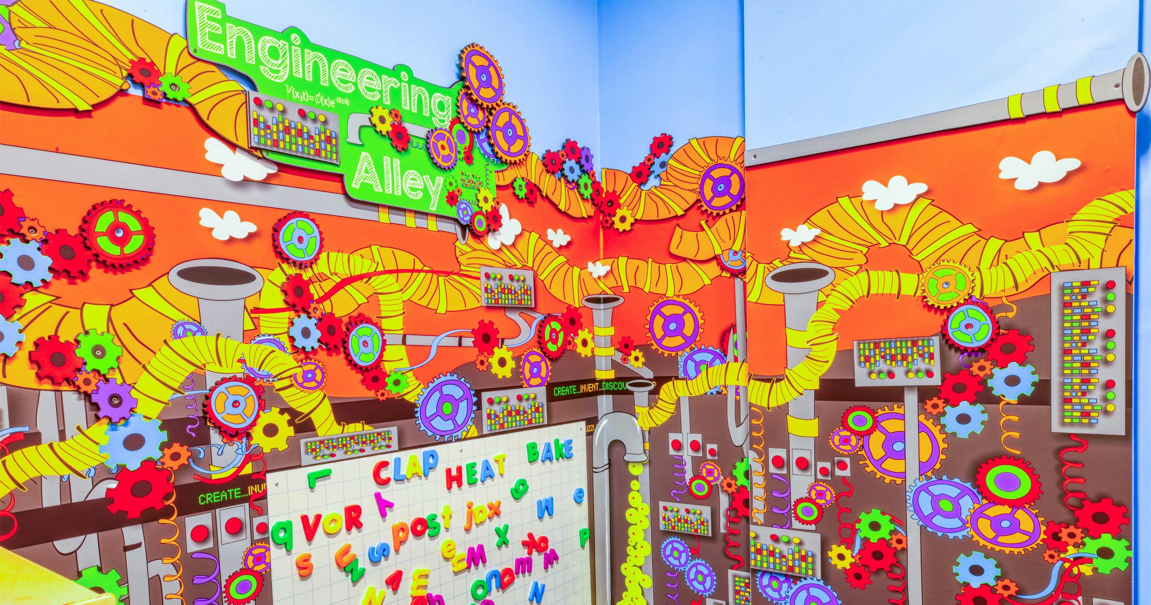 Engineering Alley sign above a colorful display of pipes and gears