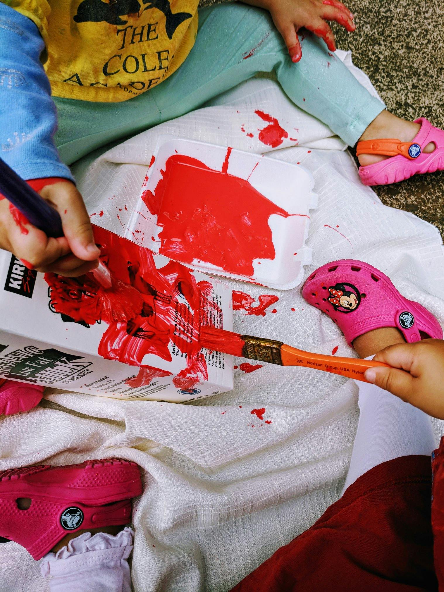 Child painting with red paint and a paintbrush