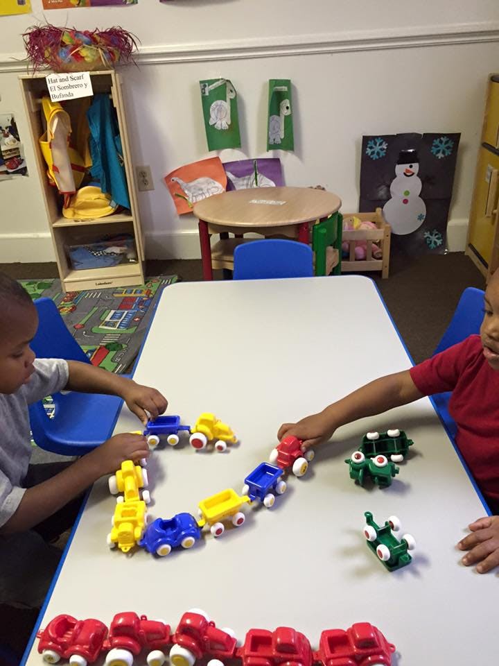 Two children playing with toy trucks at a table