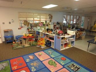 Playroom with toys, small tables, and a colorful alphabet rug