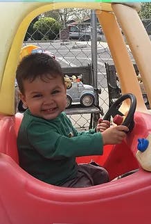 Child in a toy car holding the steering wheel