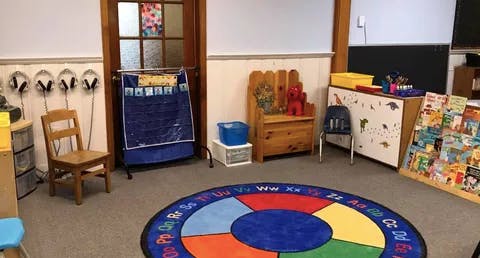 Classroom with colorful rug, small chairs, and learning materials
