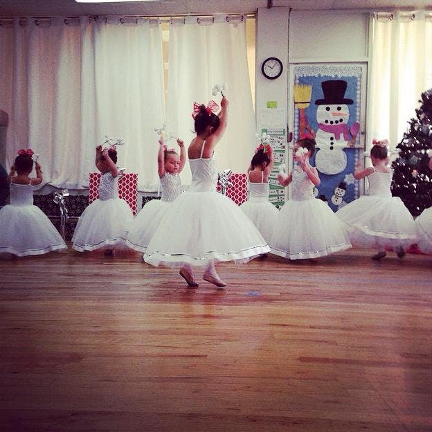 Children in white tutus dancing in a room