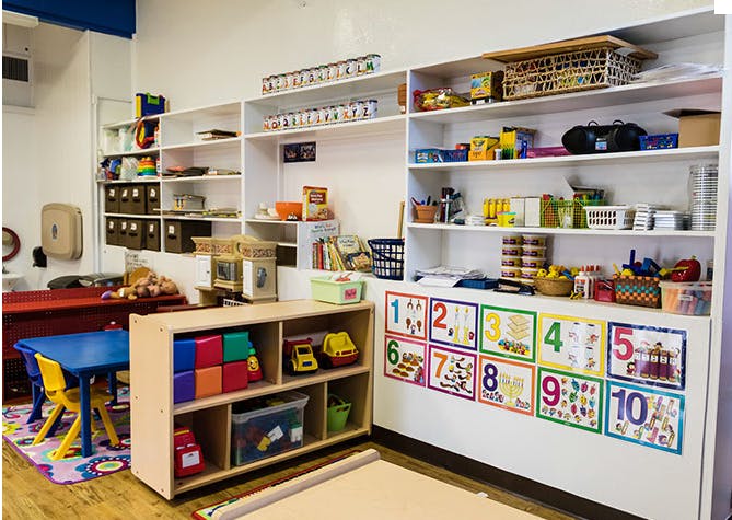 Classroom with shelves of supplies, a small table, and number charts