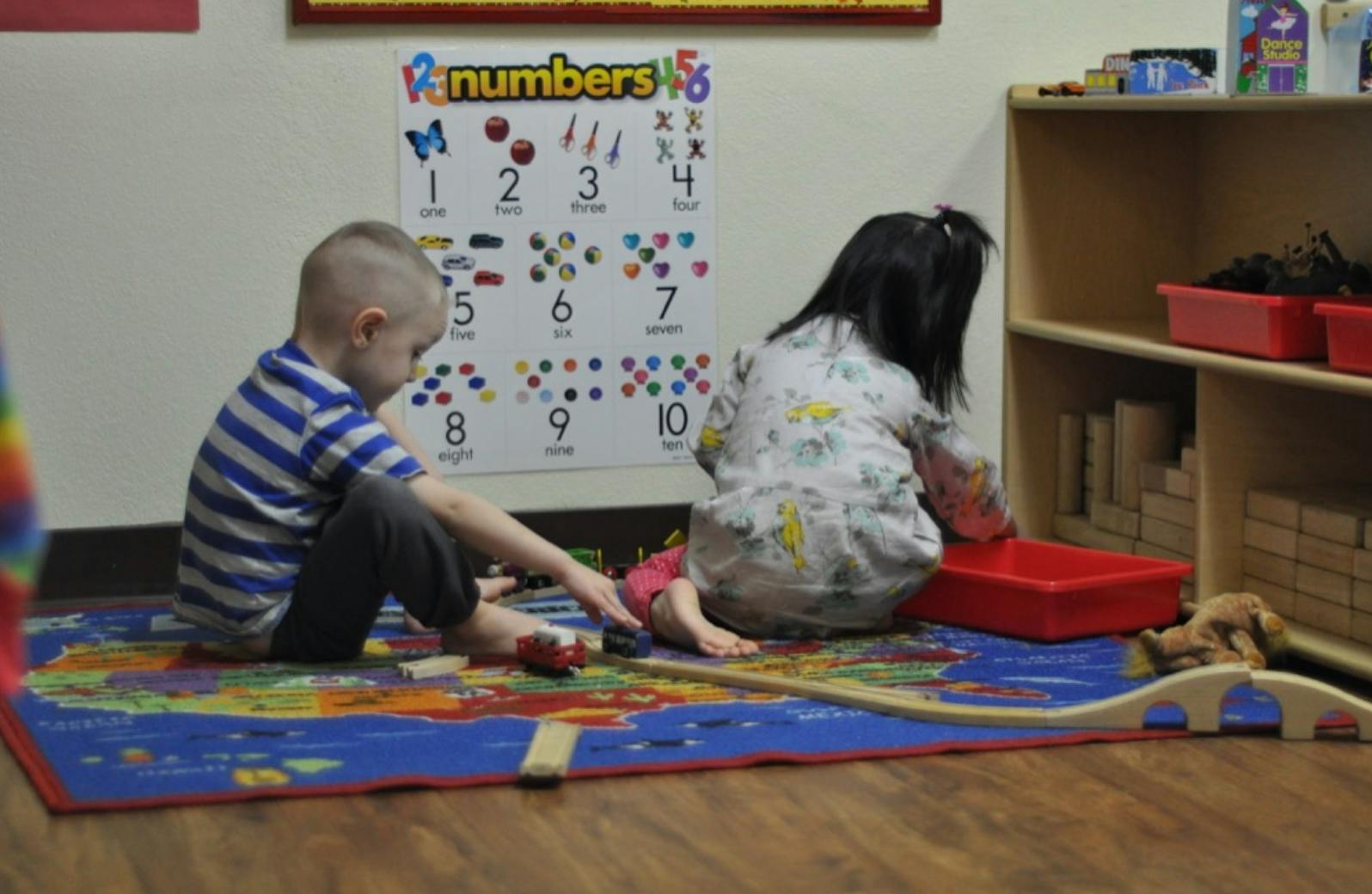 Two children playing on a rug in a classroom