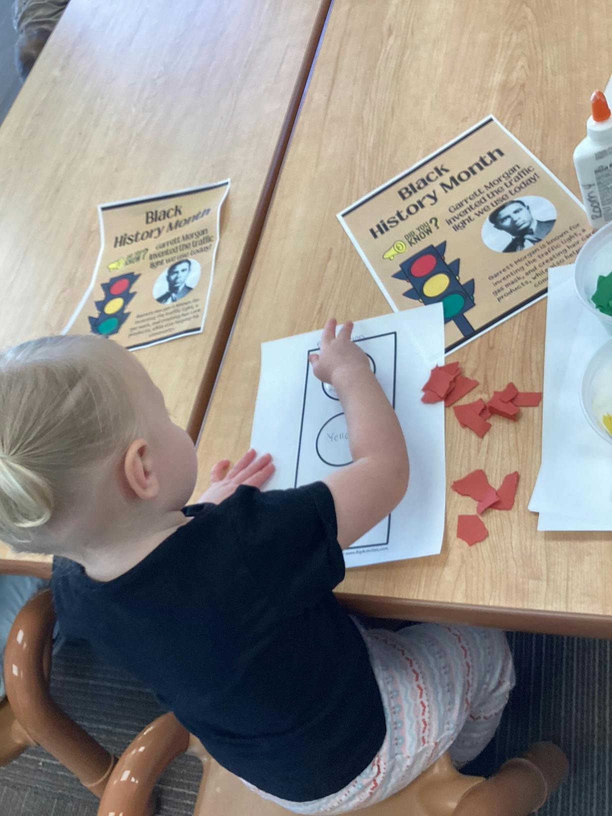 Child gluing paper pieces onto a craft project at a table