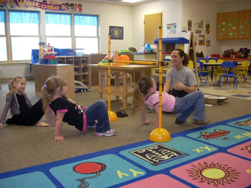 Adult and children doing crab walks in a classroom