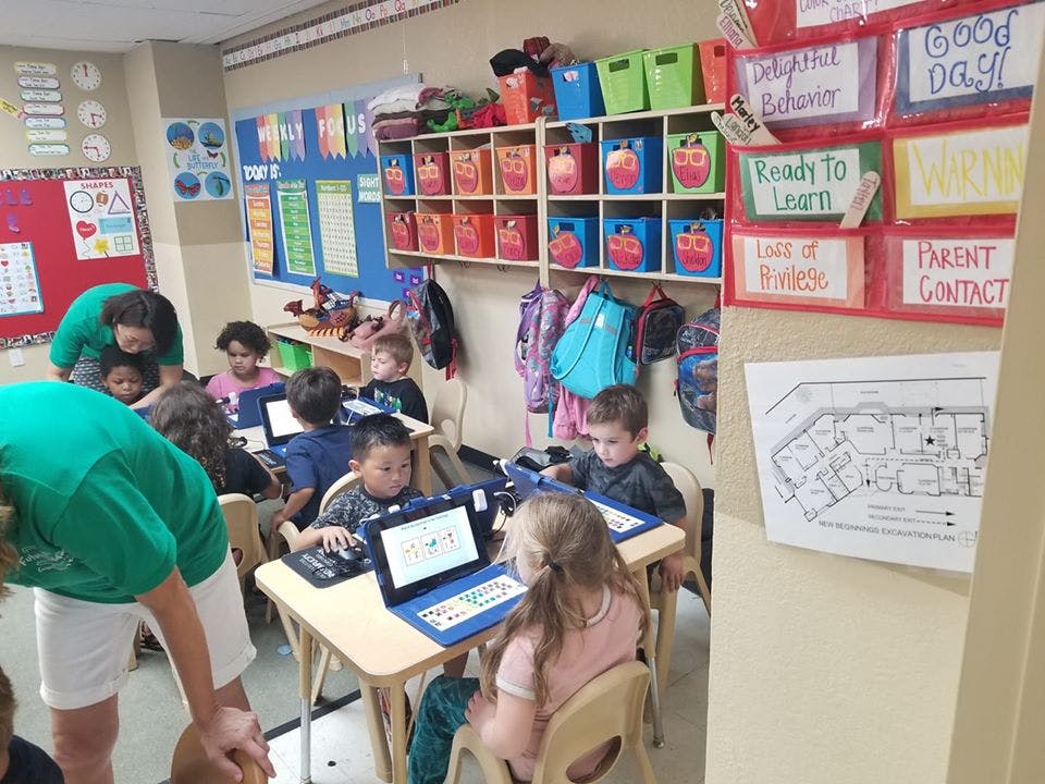 Adults and children working on laptops in a classroom