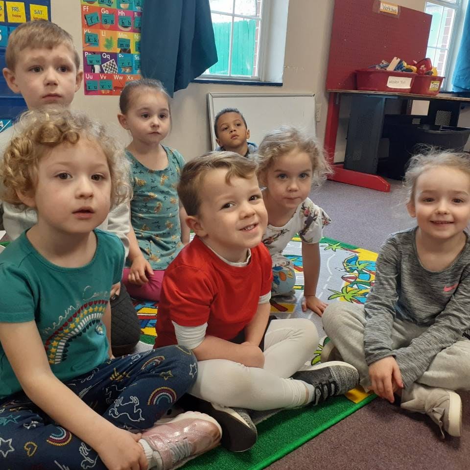 Group of children sitting on the floor in a classroom