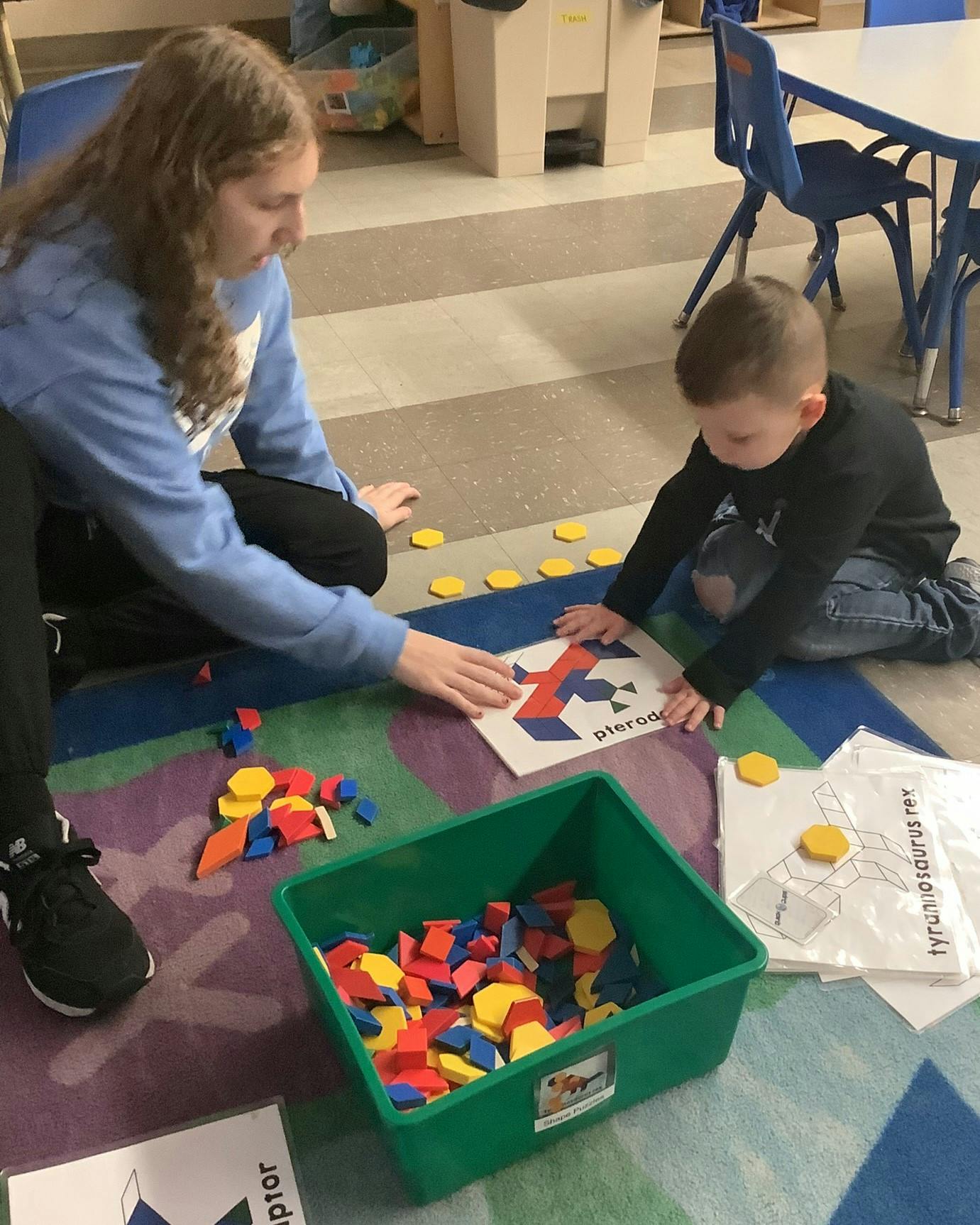 Person and child playing with colorful geometric shapes on the floor