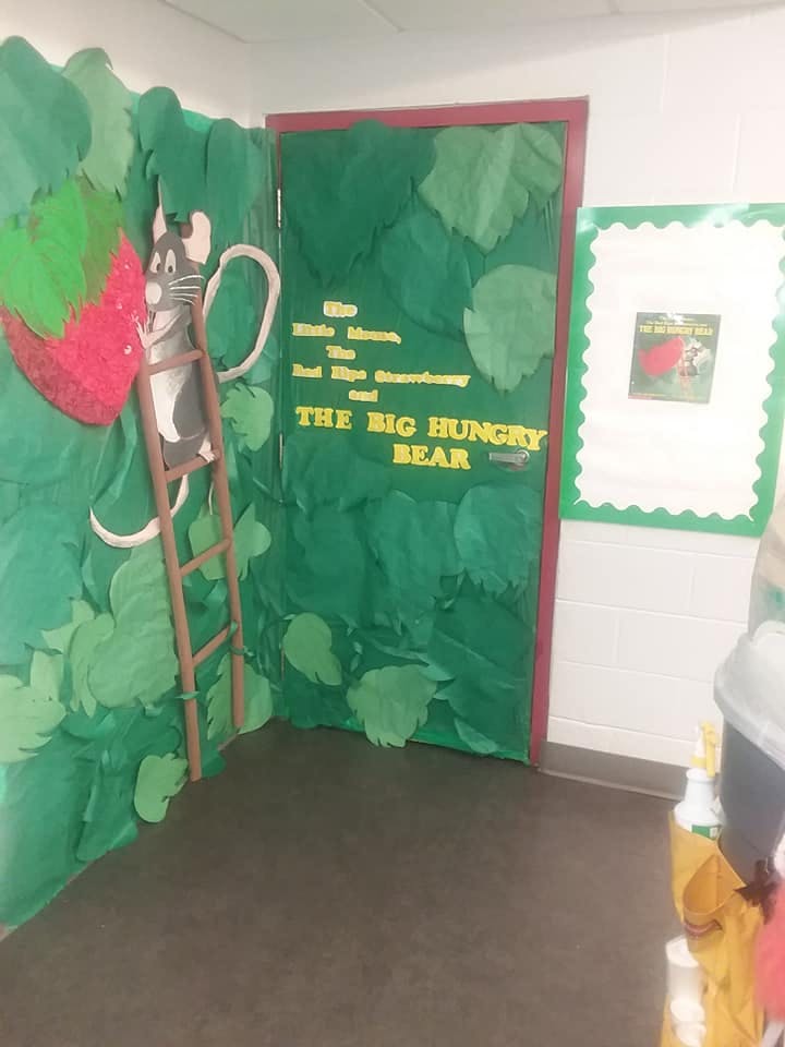 Classroom door decorated with green leaves, a mouse on a ladder, and text