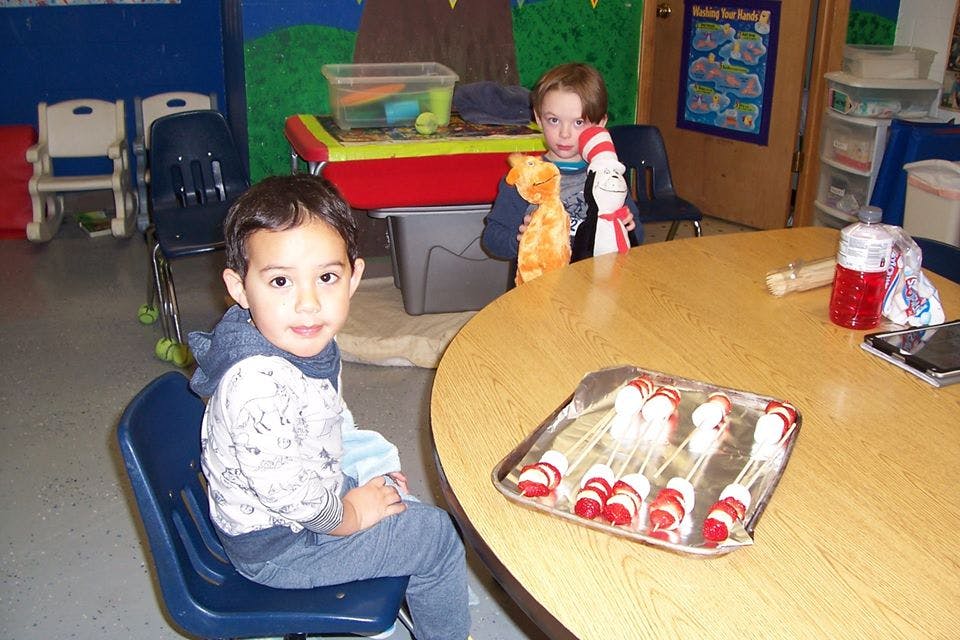 Two children at a table with food on skewers
