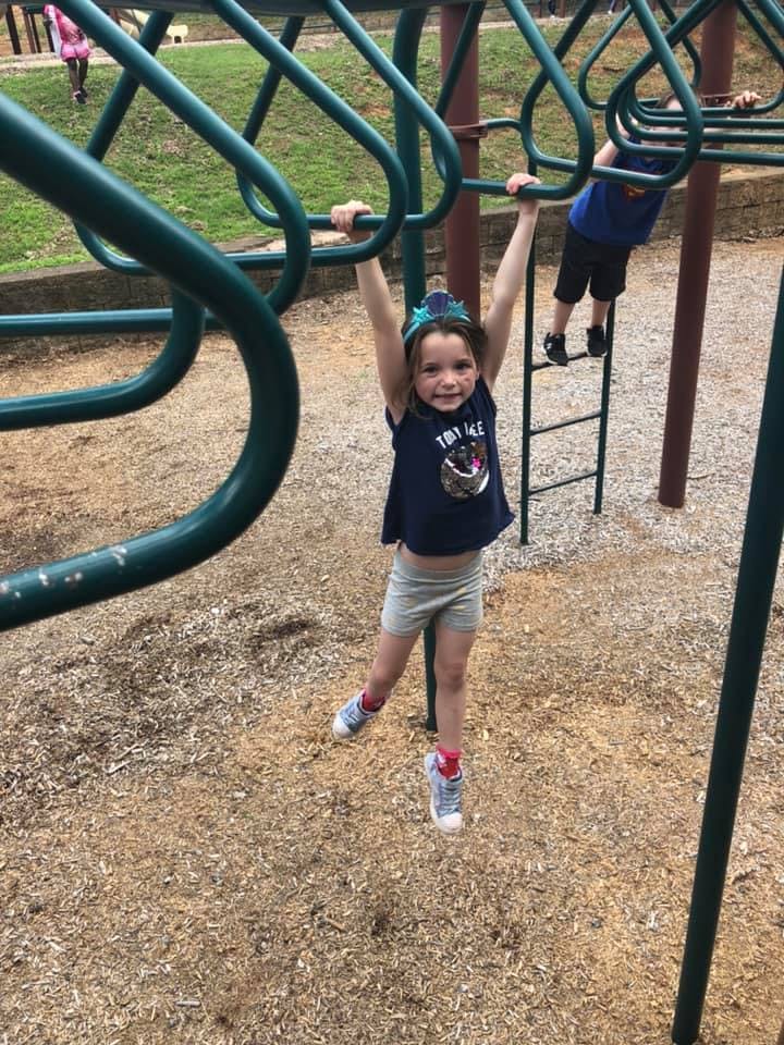 Child hanging from monkey bars on a playground