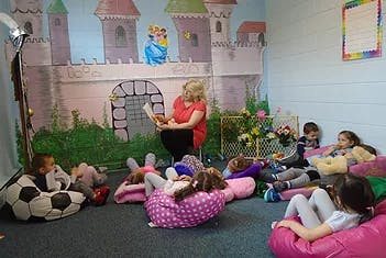 Adult reading to children in a room with a castle mural