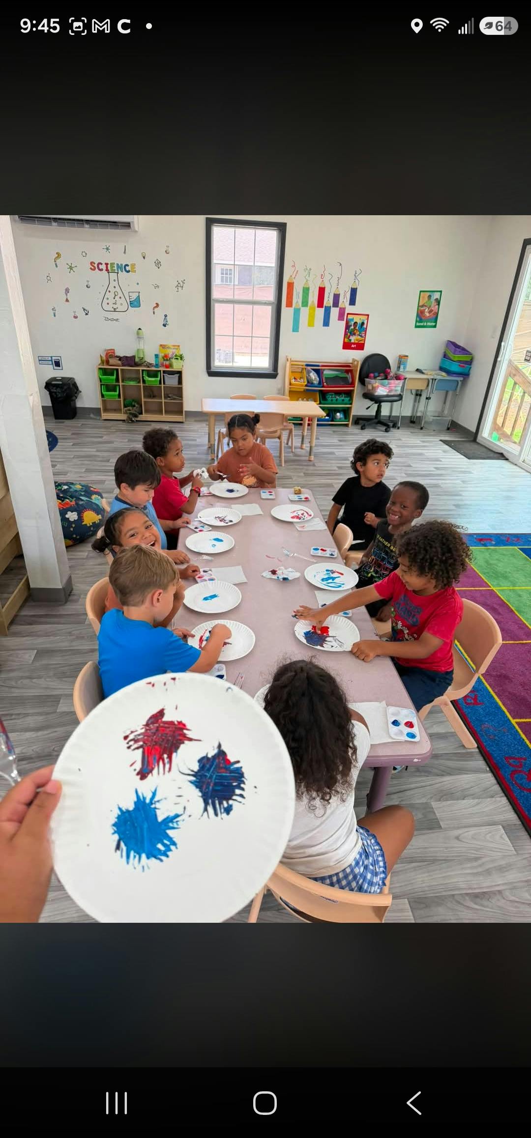 Group of children at a table painting on paper plates in a classroom
