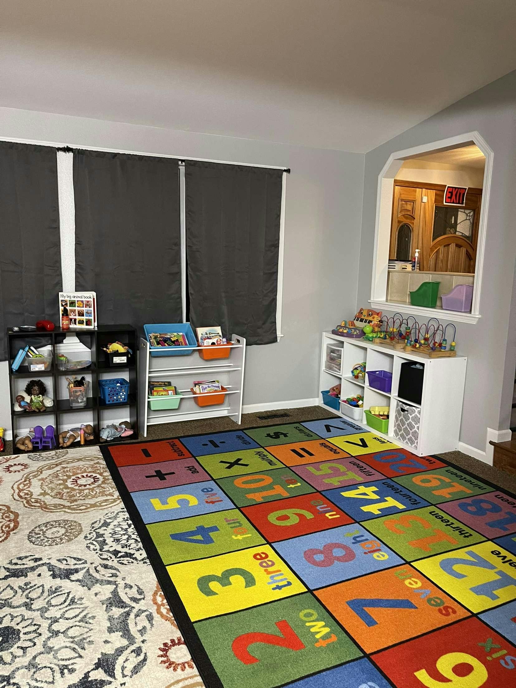 Playroom with colorful number rug, toy shelves, and window