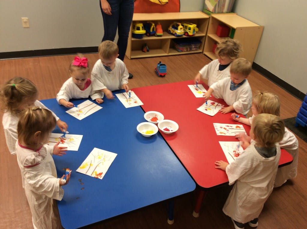 Children painting at a table in a classroom