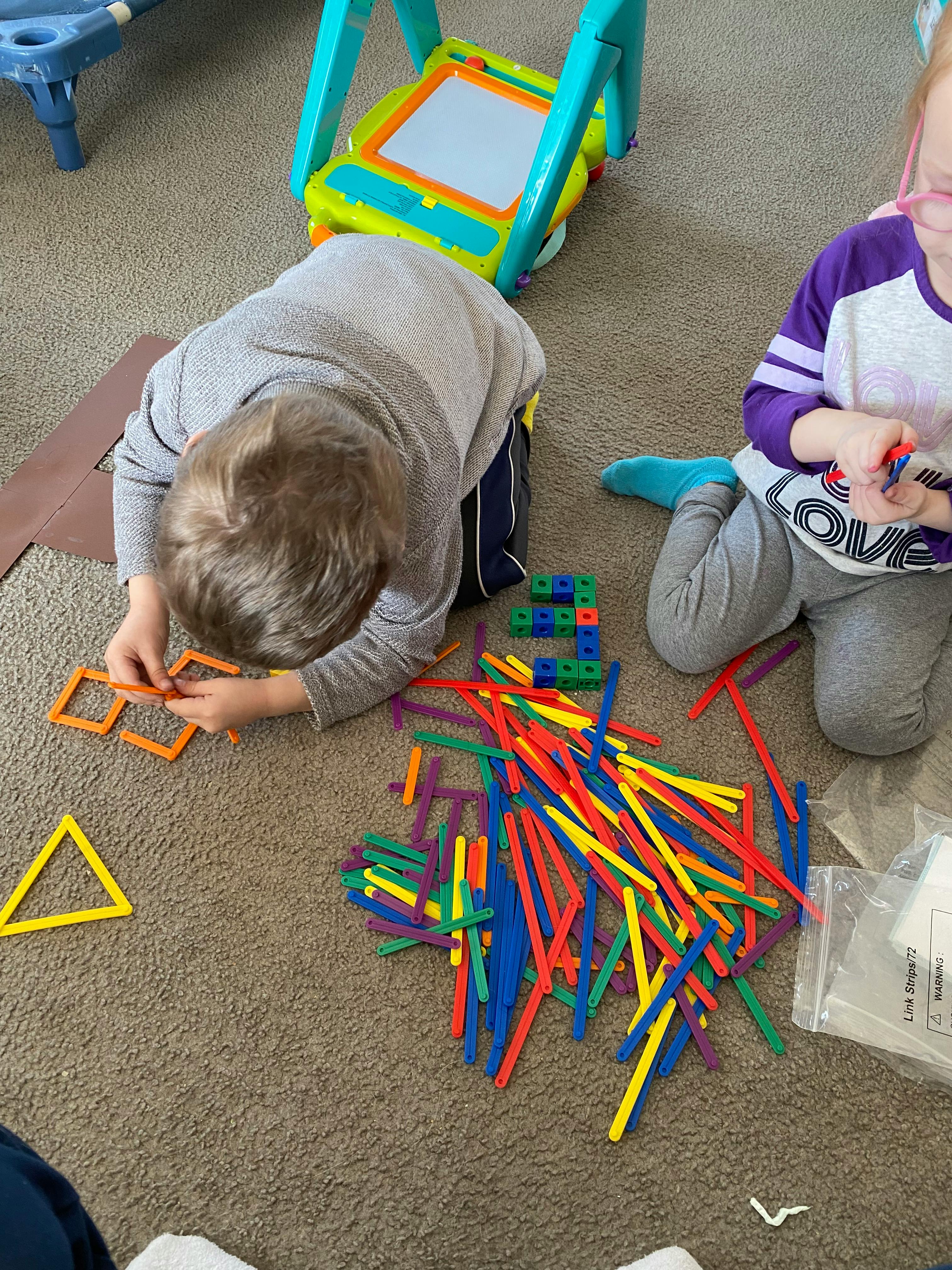 Child playing with colorful building sticks on the floor