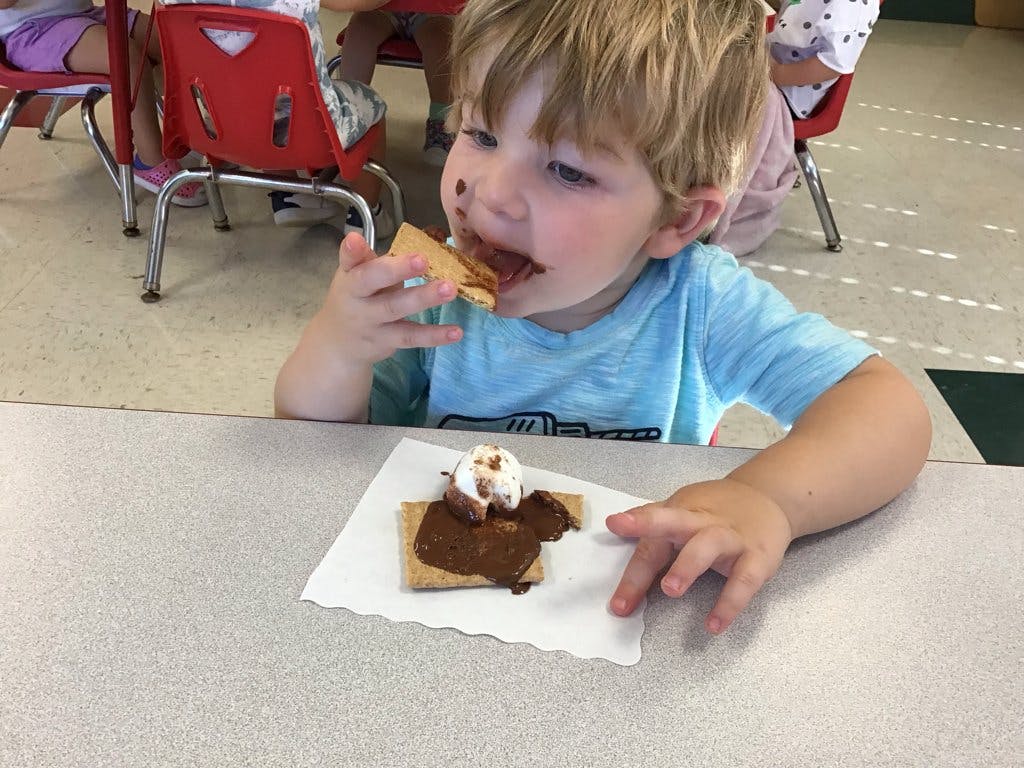 Child eating a s'more, chocolate on face