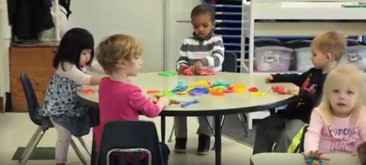Children playing with colorful toys at a round table in a classroom