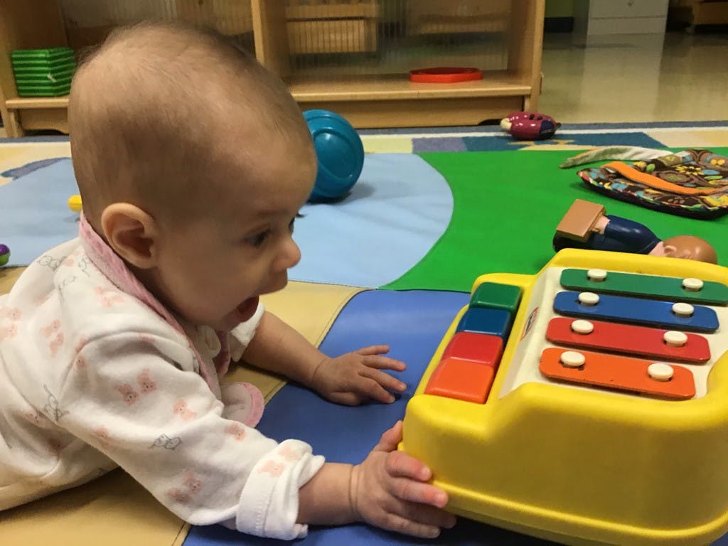 Child on floor playing with a toy xylophone