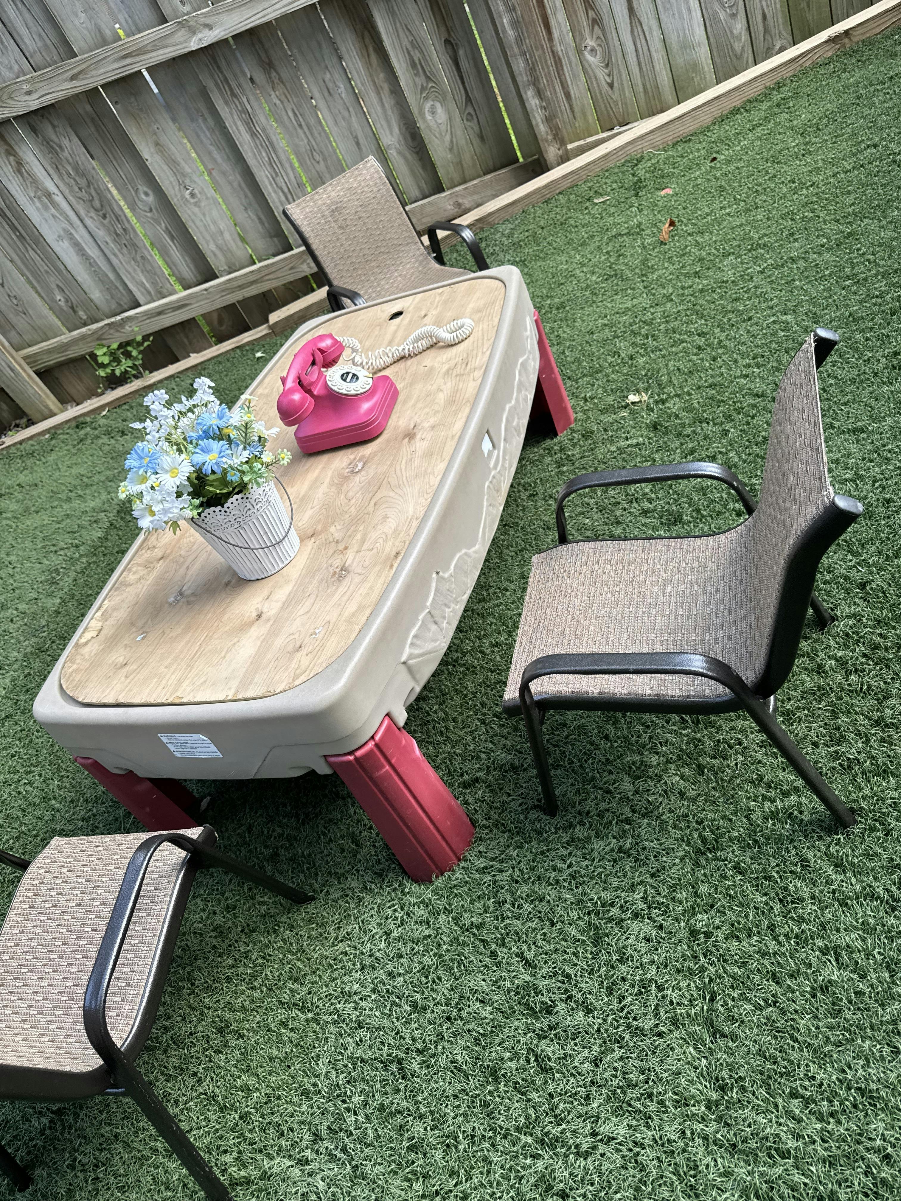 Plastic table with chairs and a rotary phone on artificial grass
