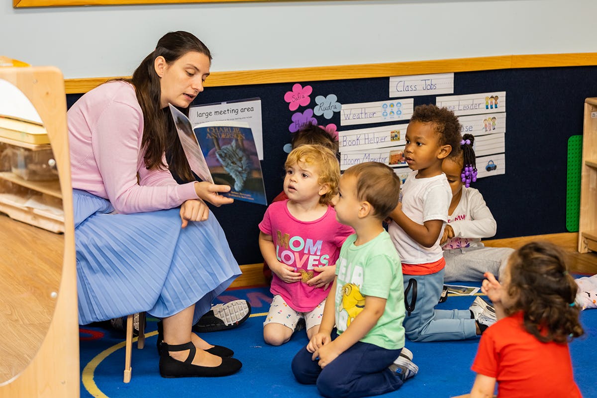 Person reading a book to a group of children in a classroom