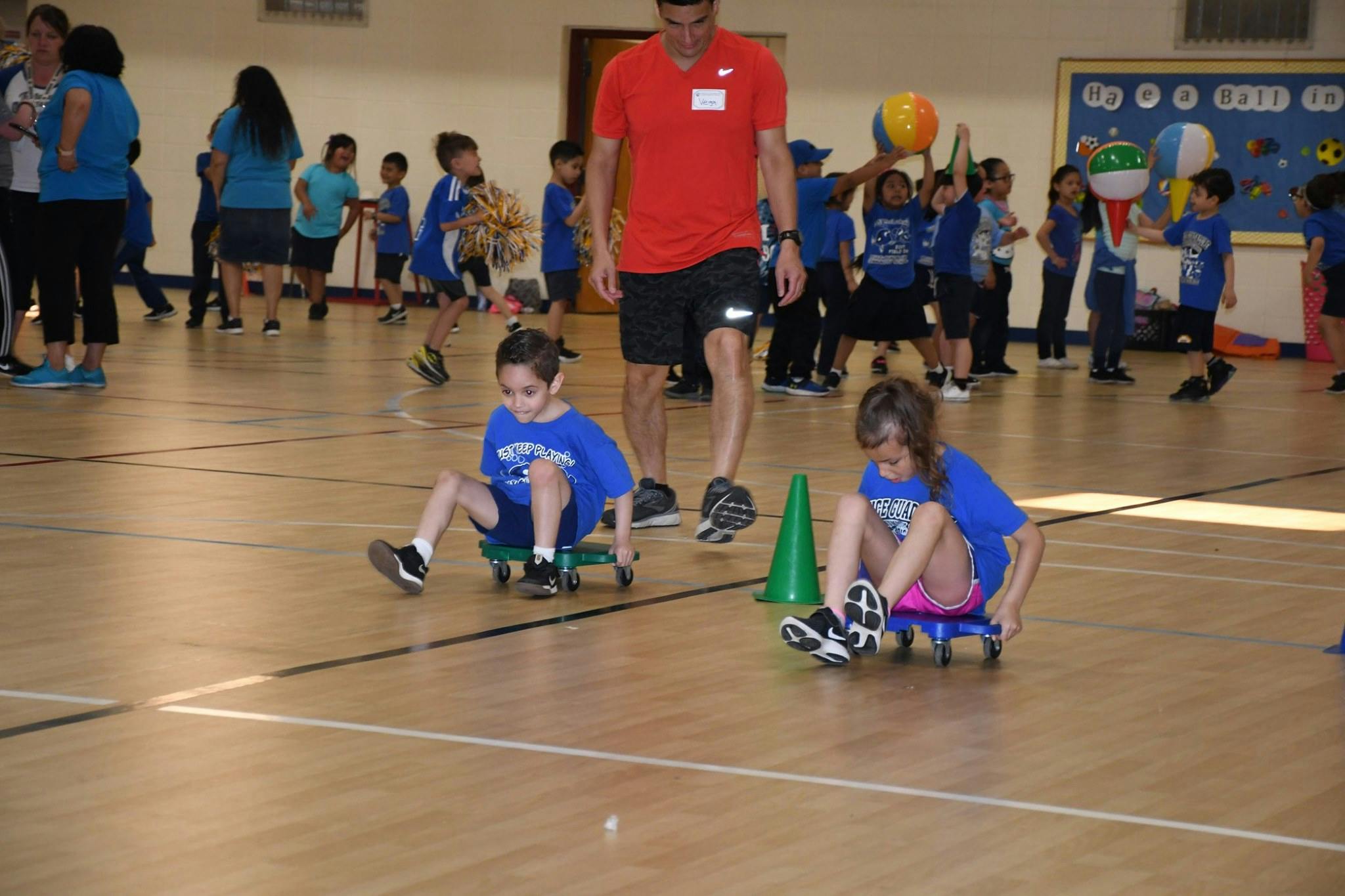 Two children sitting on scooter boards in a gym