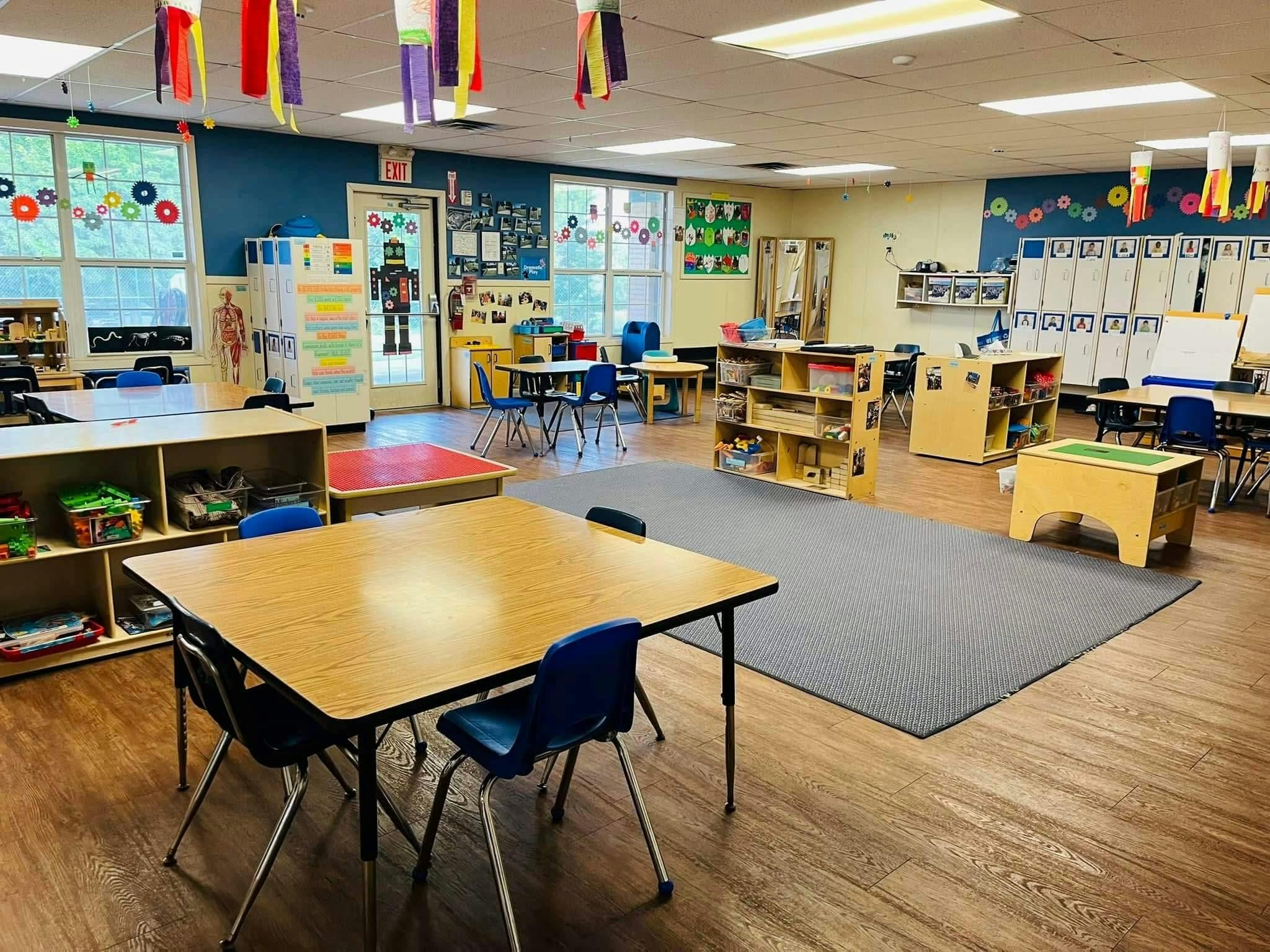 Empty classroom with small tables and chairs, shelves, and decorations