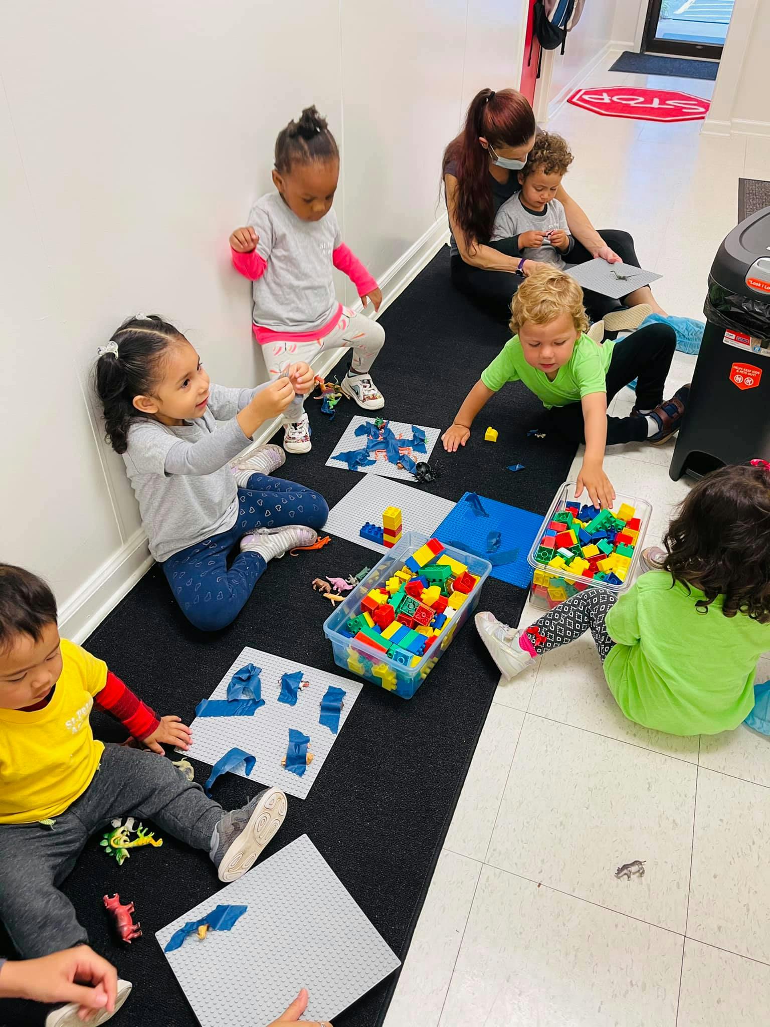 Children playing with building blocks and a person supervising