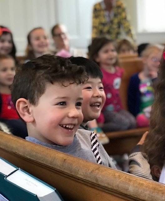 Two children smiling in a row of seats