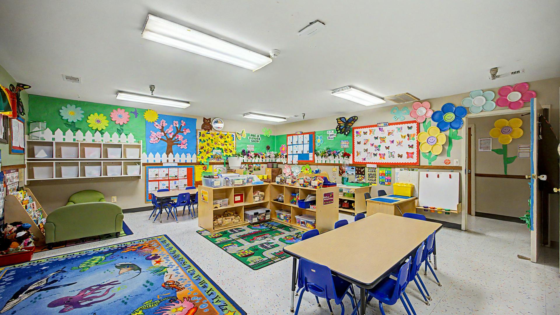 Colorful preschool classroom with tables, chairs, and play mats