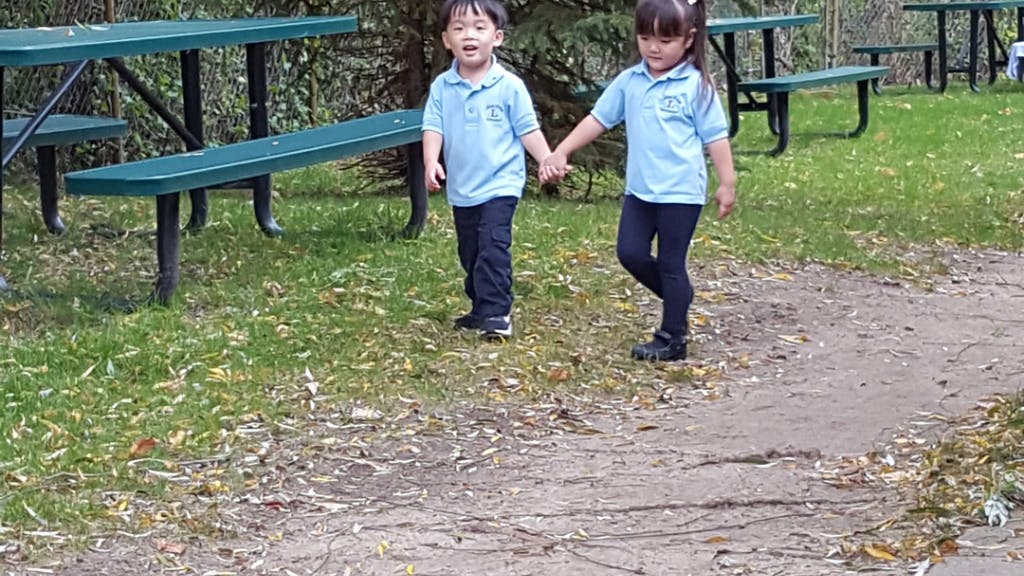 Two children holding hands and walking on a path