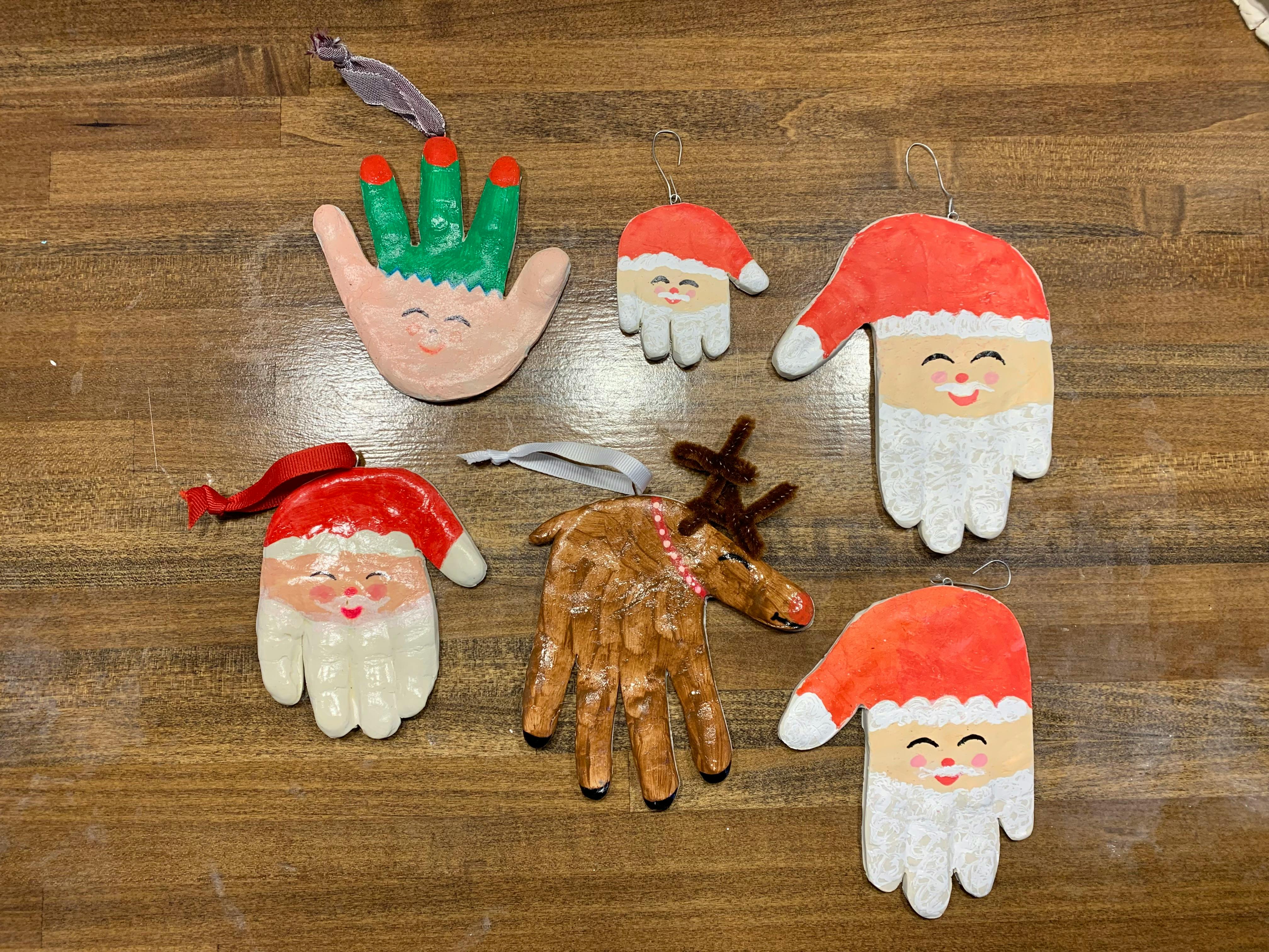 Handprint ornaments shaped like Santa, an elf, and a reindeer