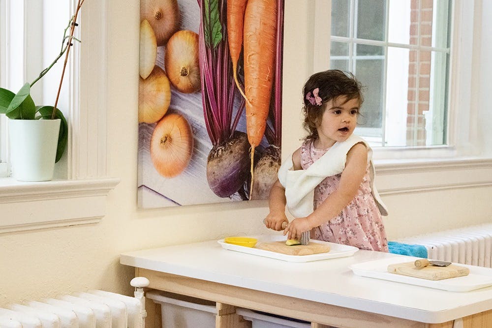 Child cutting food on a table in a classroom