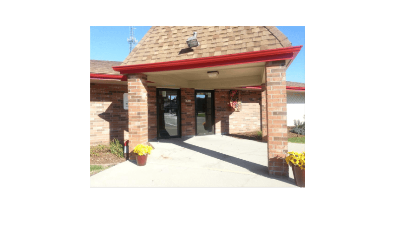 Entrance to a brick building with a brown roof and red gutters
