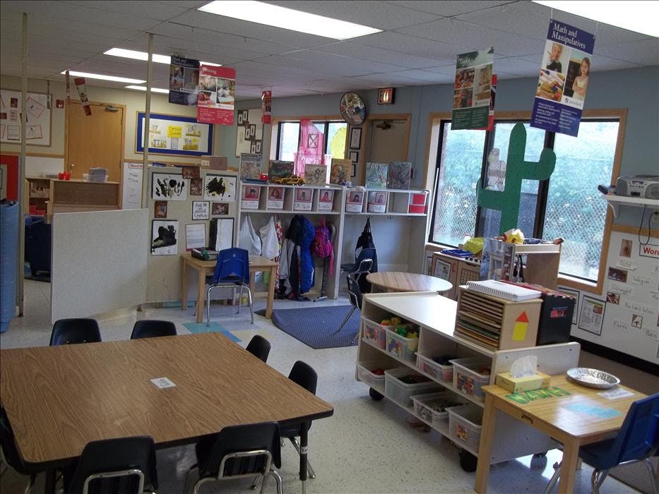 Classroom with tables, chairs, shelving units, and teaching materials