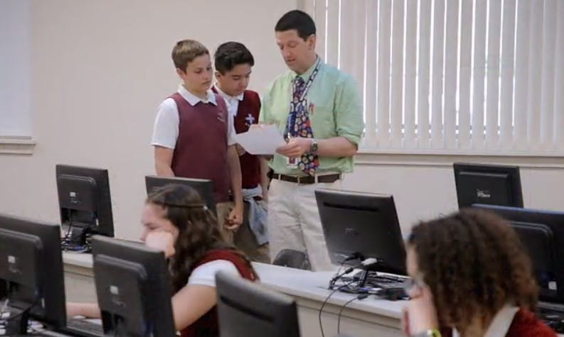 Adult and two teens looking at paper in a computer lab
