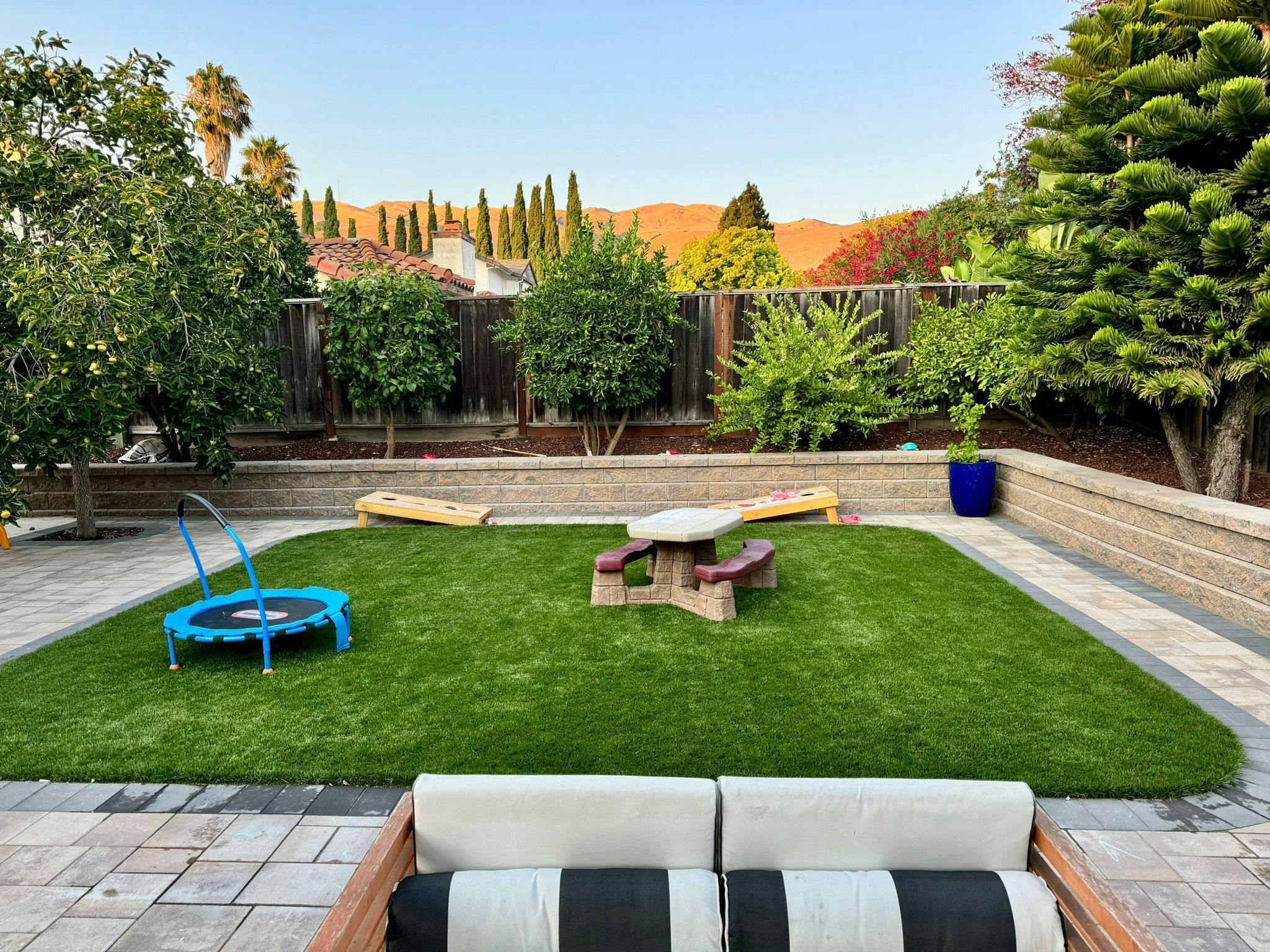 Backyard with green lawn, small trampoline, and picnic table