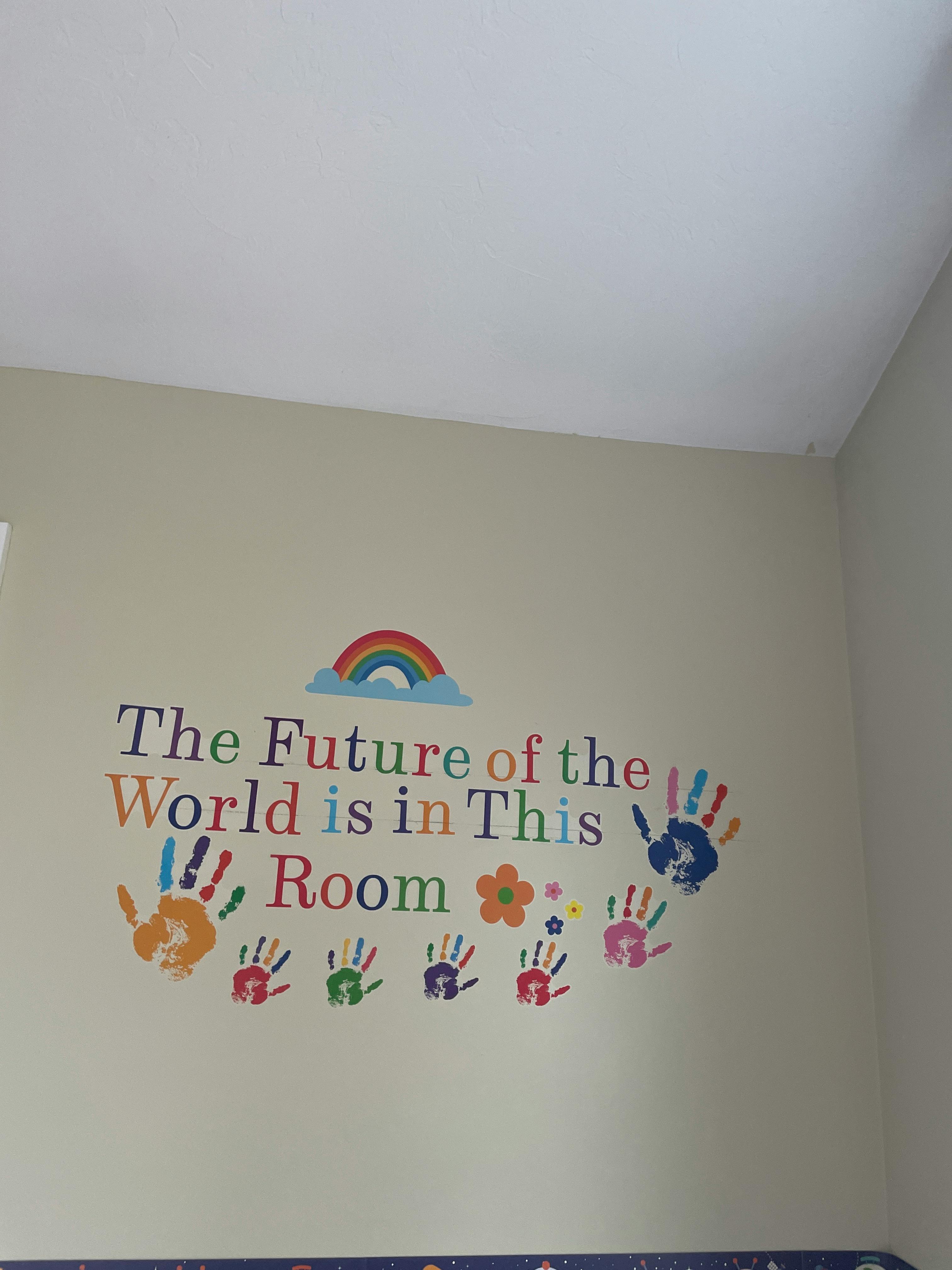 Wall decal with text "The Future of the World is in This Room" and handprints