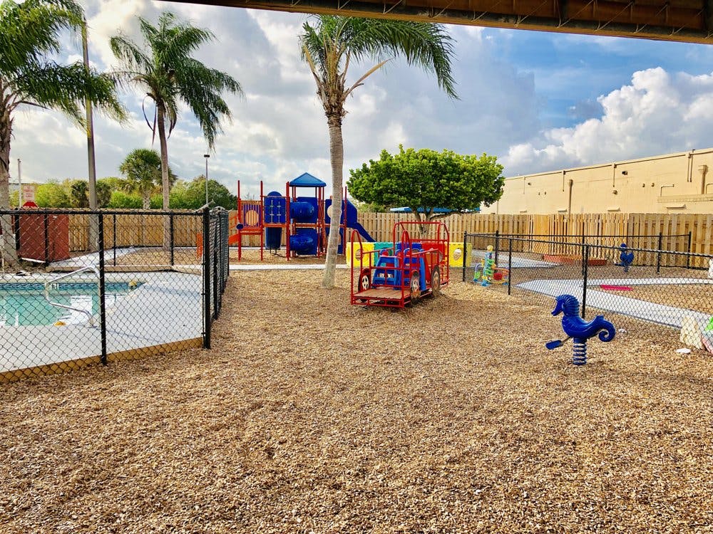 Outdoor playground with a pool, play structure, and spring rider