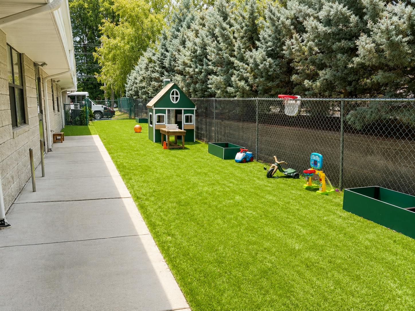 Playground area with a small playhouse and toys on artificial grass