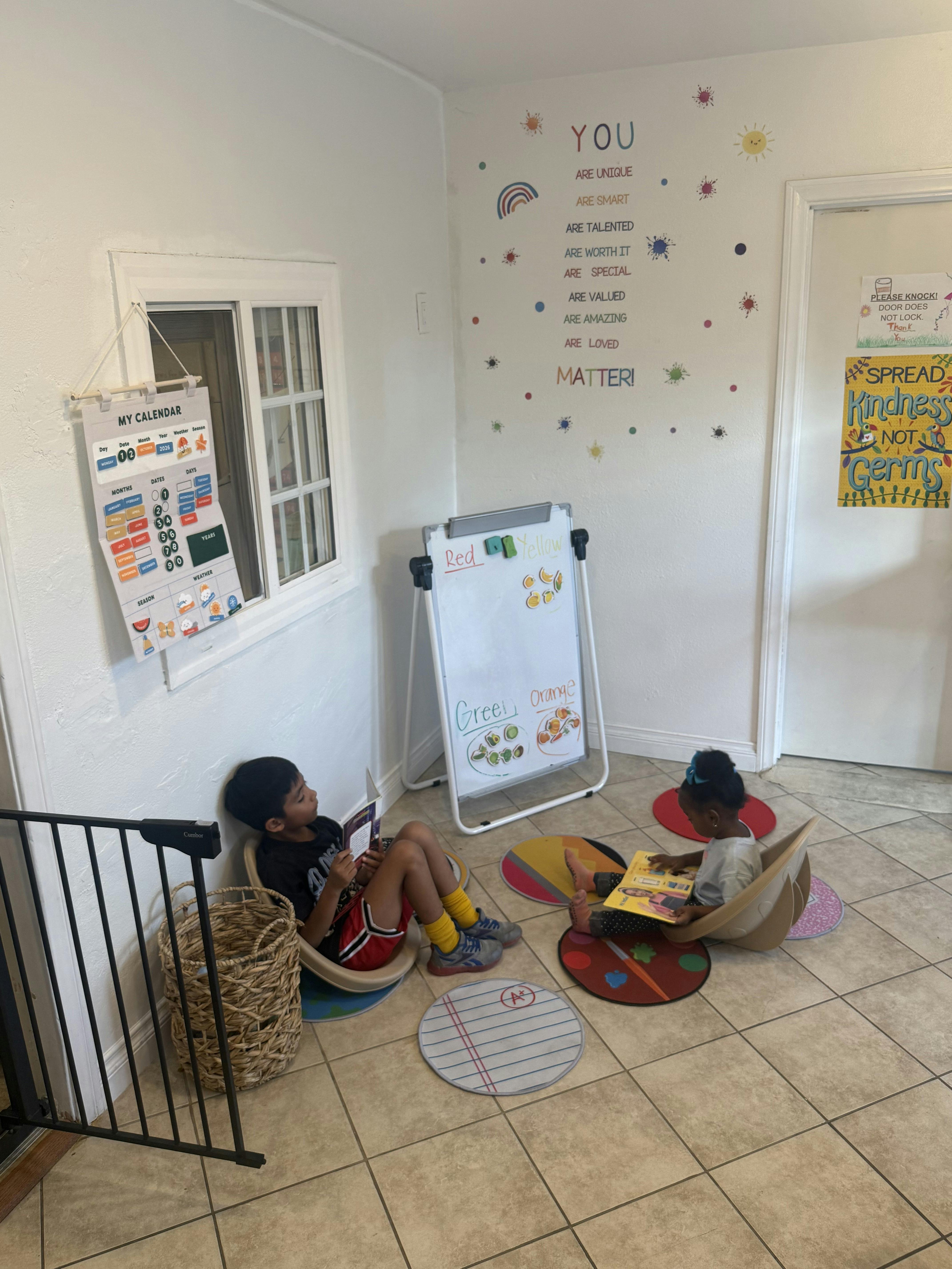 Two children sitting on the floor in a classroom reading books